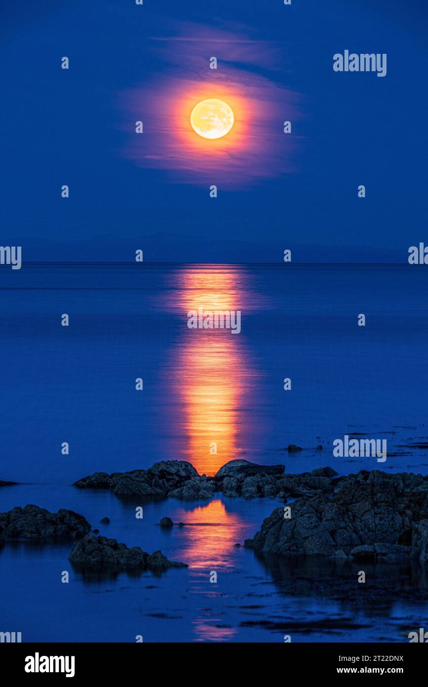 La super luna (una luna blu) del 30/8/2023 che si innalza sull'isola di Arran vista dalla penisola di Kintyre, Scozia, Regno Unito Foto Stock