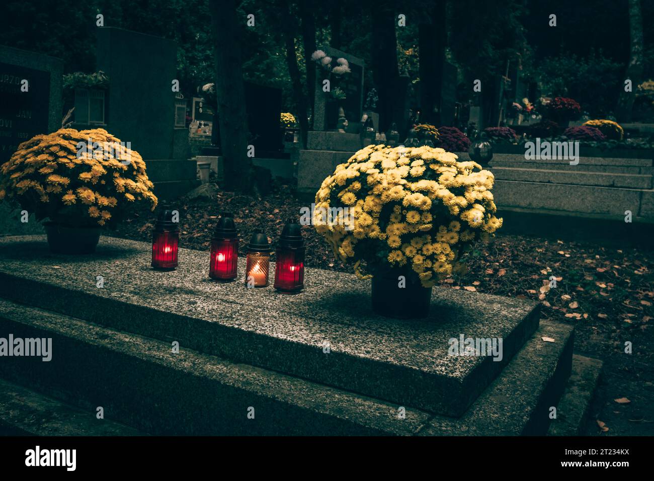Celebrazione del giorno di tutte le anime nel cimitero, decorazione tradizionale cristiana su lapide, candele, lanterne, fiori Foto Stock