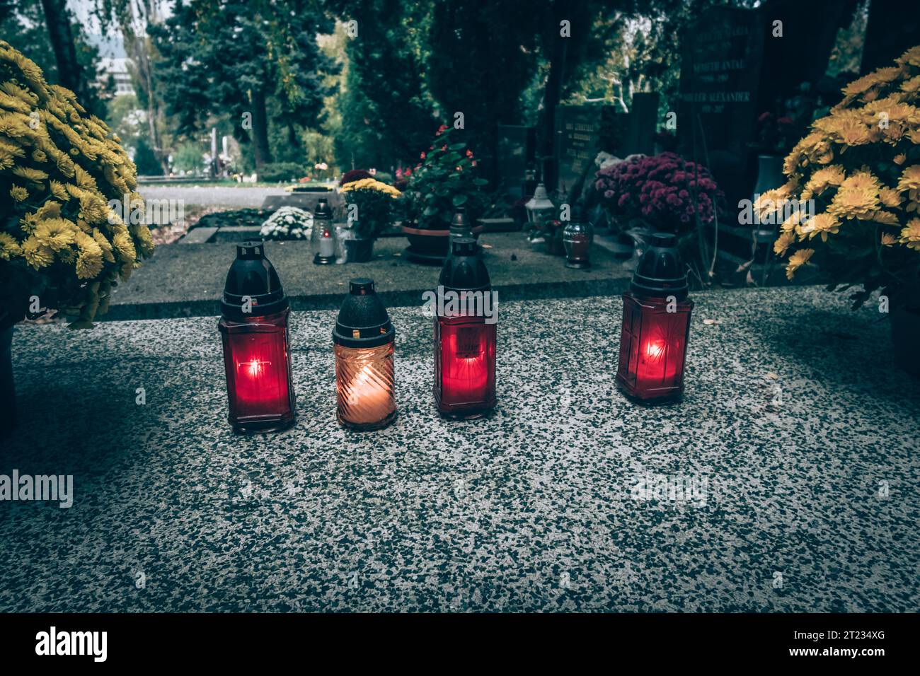 Celebrazione del giorno di tutte le anime nel cimitero, decorazione tradizionale cristiana su lapide, candele, lanterne, fiori Foto Stock