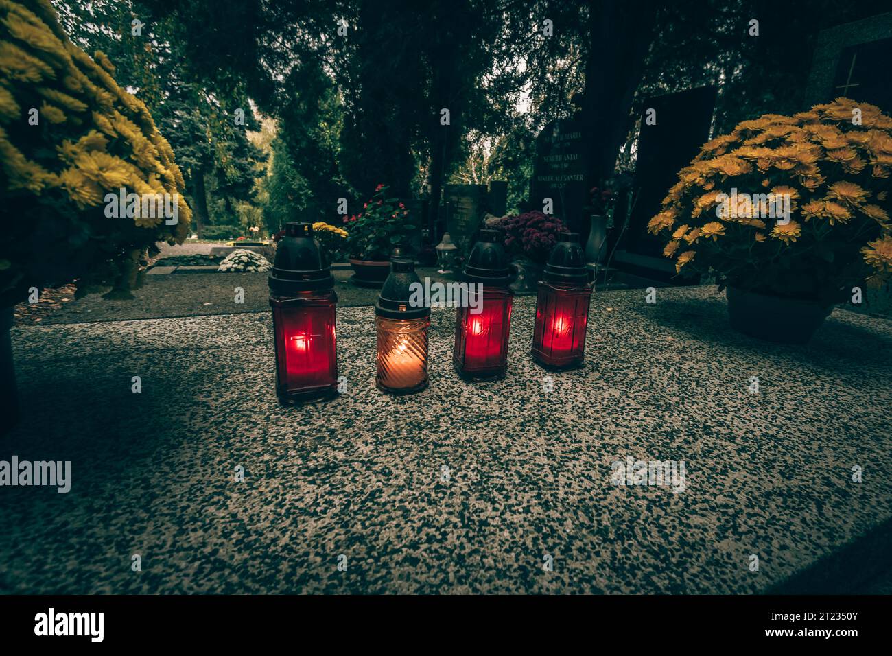 Celebrazione del giorno di tutte le anime nel cimitero, decorazione tradizionale cristiana su lapide, candele, lanterne, fiori Foto Stock