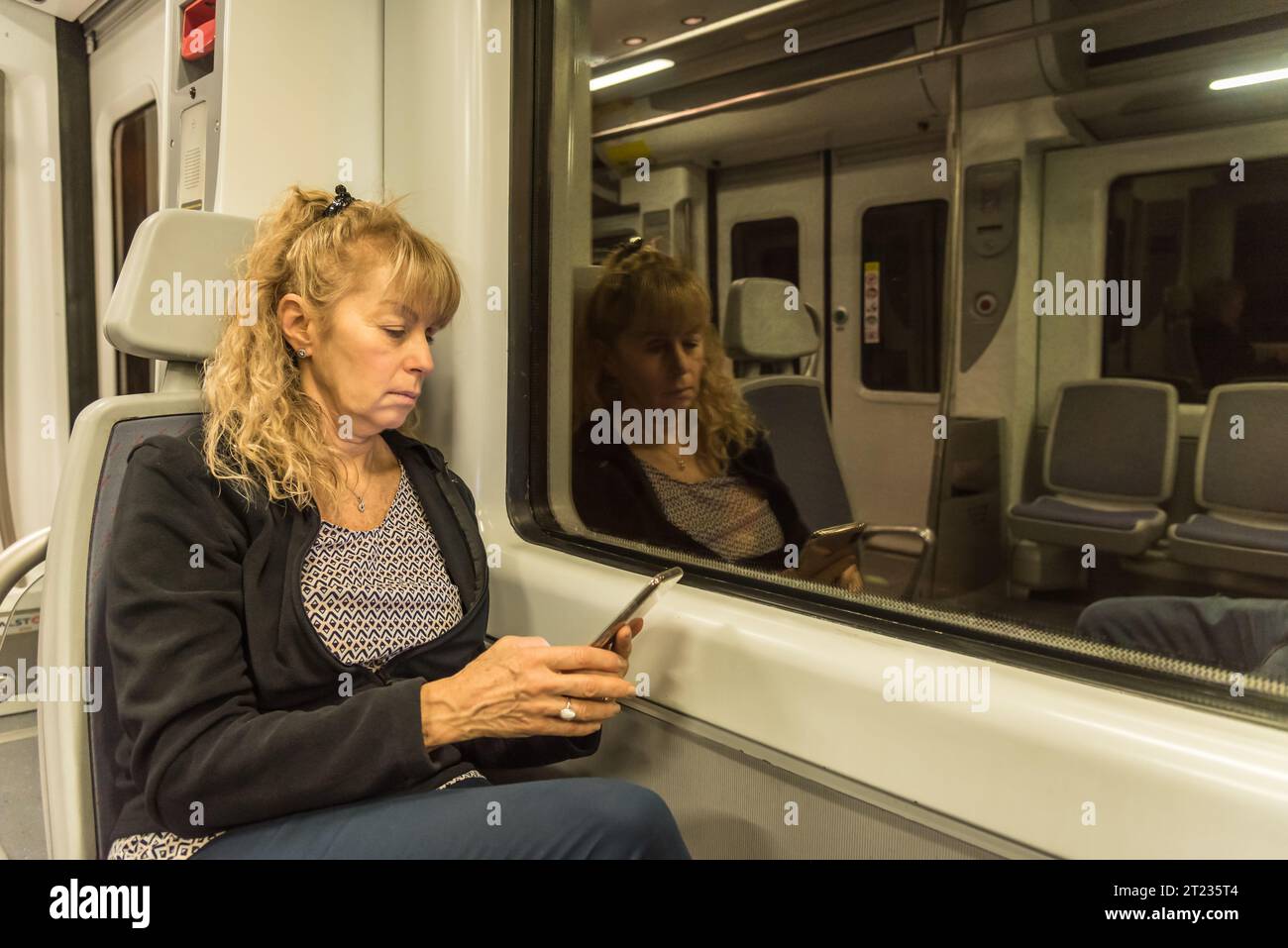 Donna adulta che viaggia da sola sul treno e guarda un cellulare. Concetto di viaggio Foto Stock
