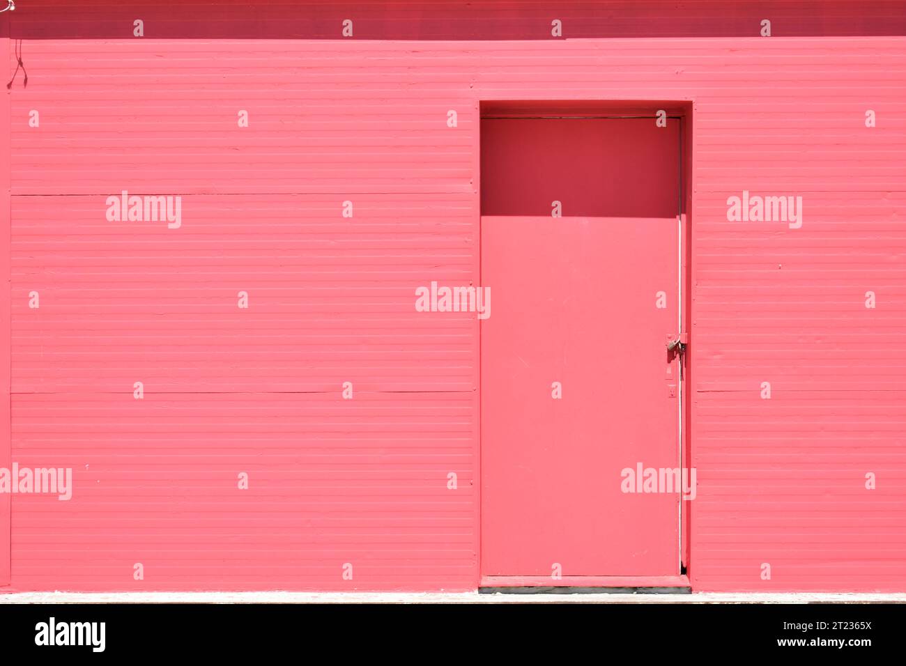 Semplice porta rosa chiusa su una vecchia parete dipinta di rosa Foto Stock