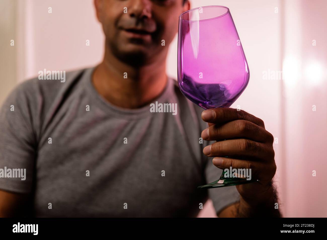Sconosciuto uomo caucasico adulto irriconoscibile che chiede un drink tenendo in mano una vetra vuota e colorata. Foto Stock