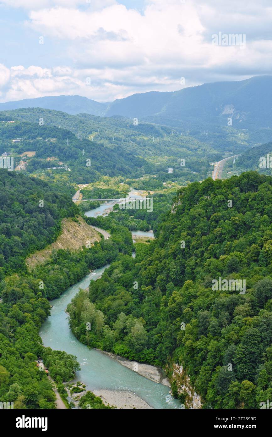 Paesaggio montano della valle del fiume. Splendido paesaggio con fiume e autostrada. Foto verticale. Regione di Sochi. Foto Stock