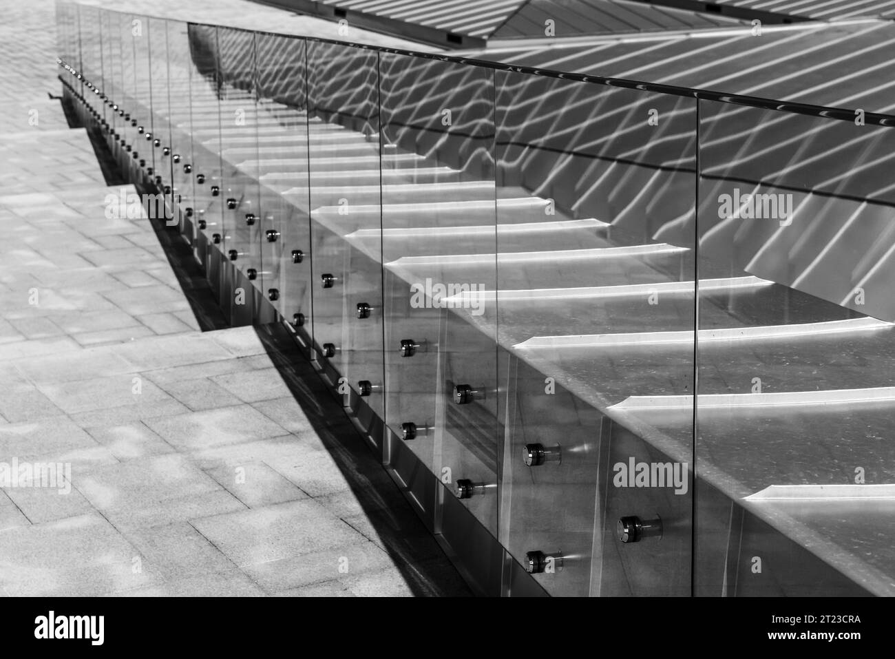 Prospettiva di un tetto lucido, corrimano e scalinata in pietra che scende. Foto astratta di sfondo dell'architettura moderna. Foto in bianco e nero Foto Stock