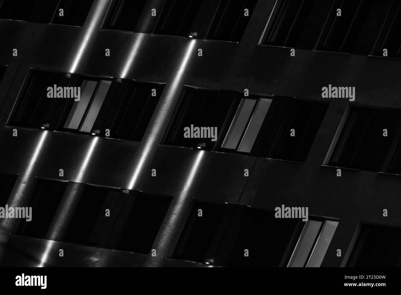 Facciata scura di notte con linee di illuminazione e sfondo architettonico astratto. Foto in bianco e nero Foto Stock