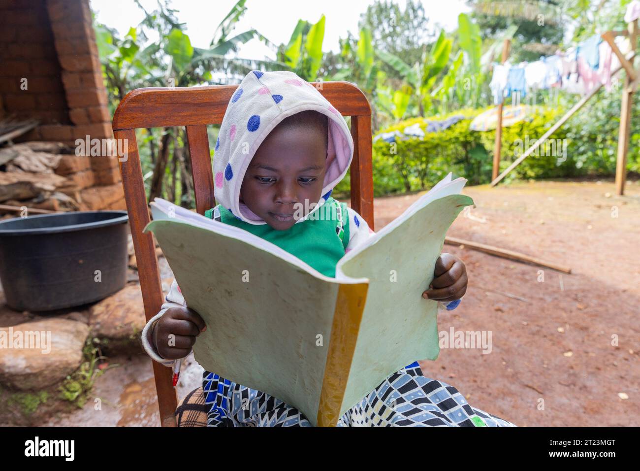 Un bambino africano concentrato che studia seduto su una sedia a casa. Foto Stock