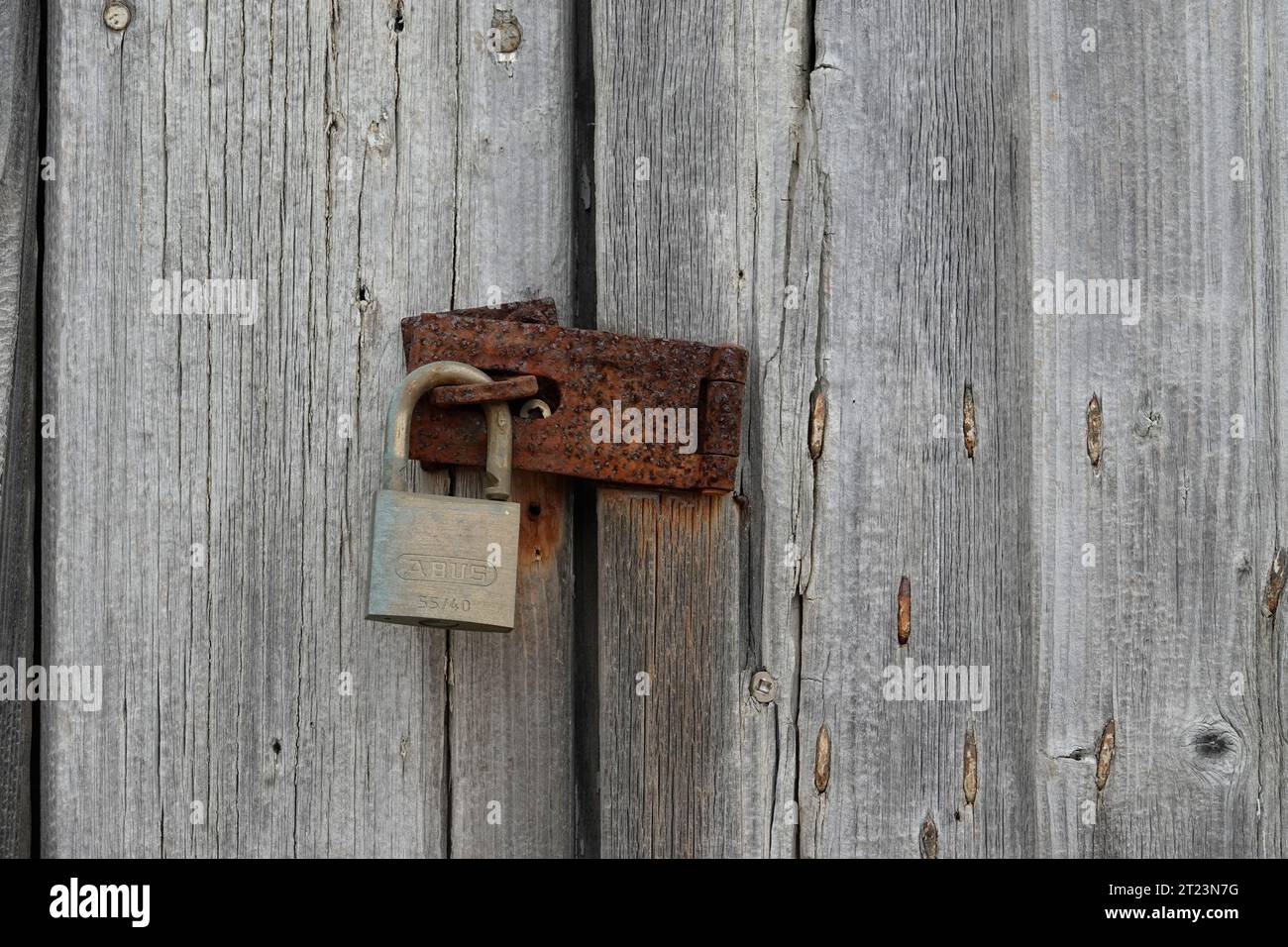 Avverto il lucchetto di ottone e un arrugginito ha la guardia e la vecchia porta intemprata Foto Stock