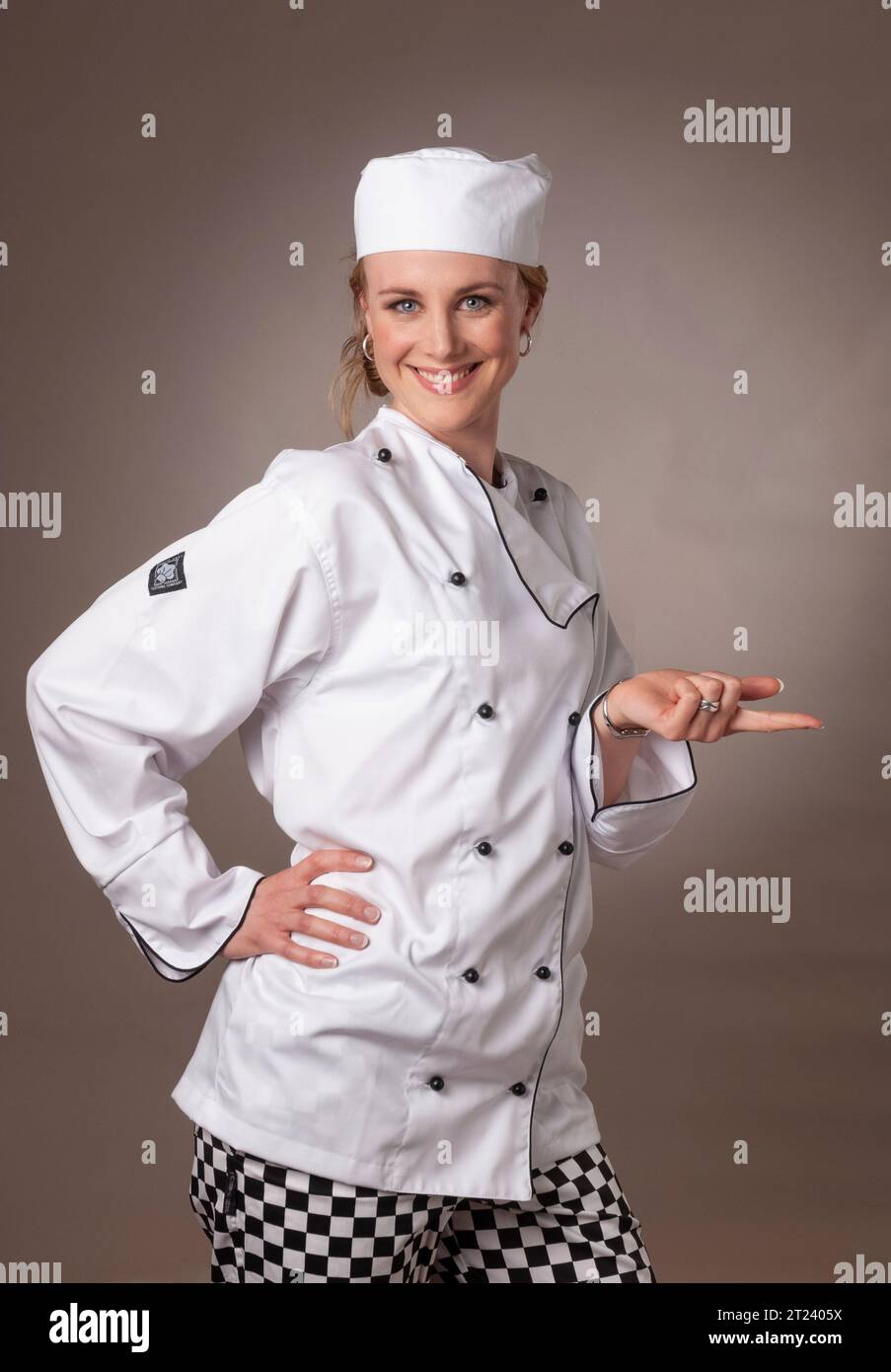 Attraente chef donna in bianco, che sembra bilanciare un oggetto Foto Stock