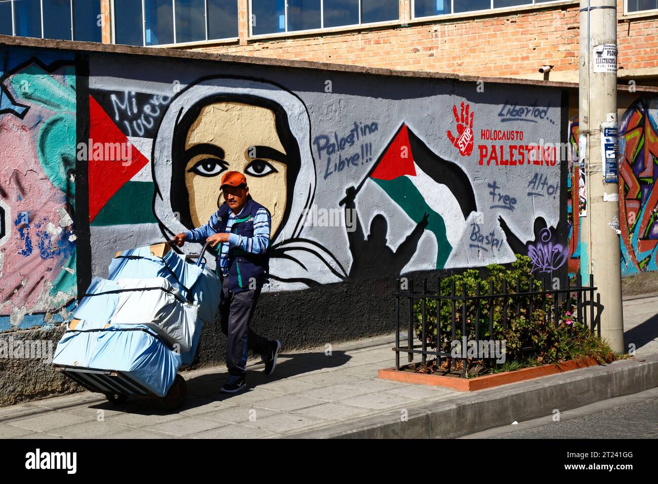 Un uomo spinge un carro davanti a un murale che mostra sostegno per una Palestina libera e chiede la fine dell'olocausto palestinese, del distretto di Miraflores, di la Paz, Bolivia. La foto è stata scattata nel settembre 2018. Foto Stock