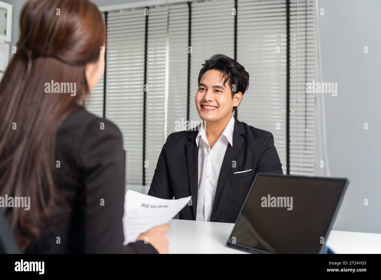 Candidato di lavoro maschile asiatico reclutato da una giovane donna d'affari adulta datore di lavoro sulla scrivania nell'ufficio aziendale mentre ha con sé un computer portatile. Concetto di reclutamento professionale Foto Stock
