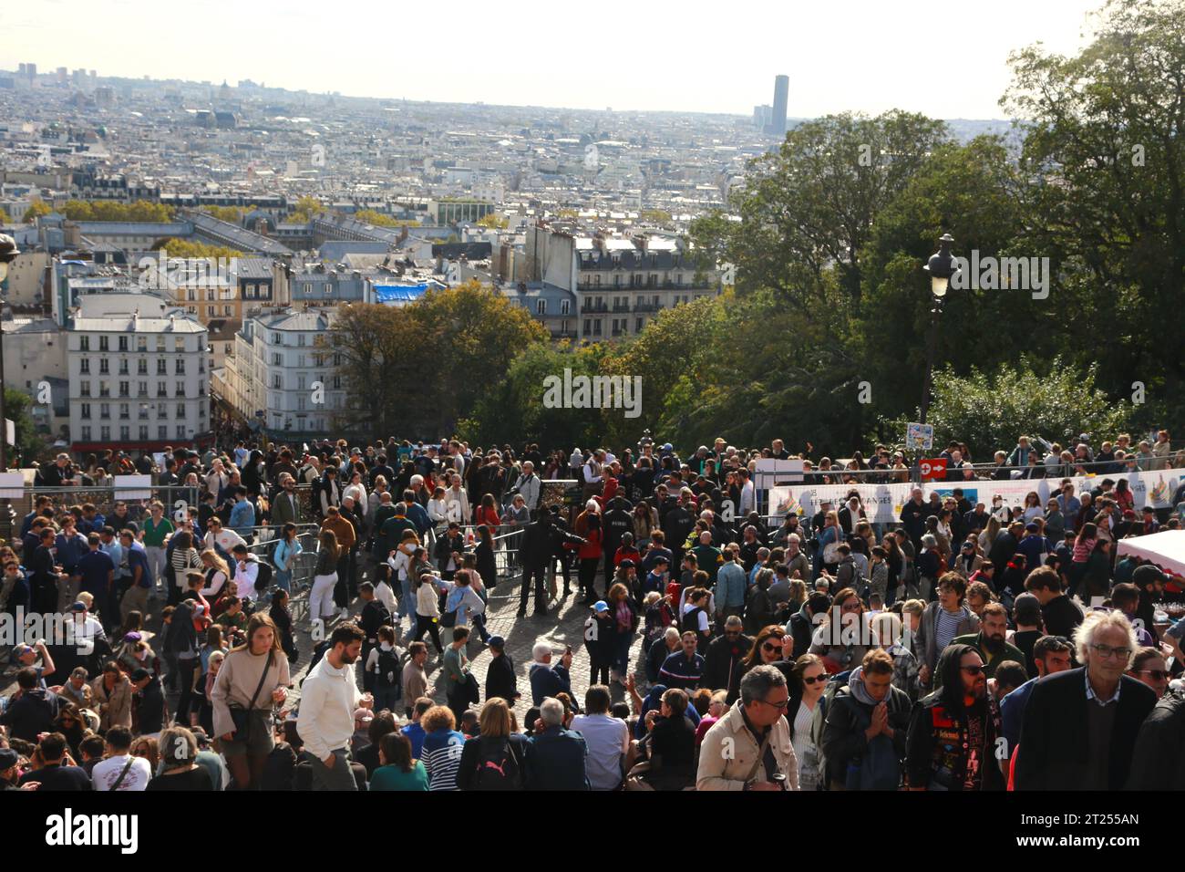 Una grande folla è riunita sotto la Cattedrale del Sacro cuore durante il Montmartre Wine Festival a Parigi, con gli edifici della città in lontananza Foto Stock