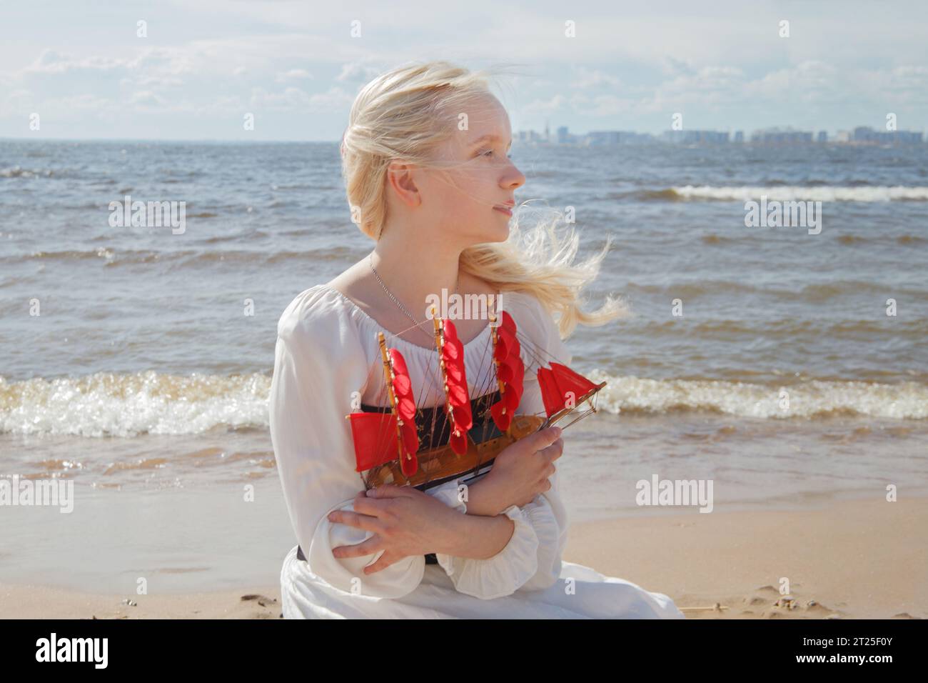 Donna bionda con barca a vela rossa contro mare spiaggia e cielo Foto Stock