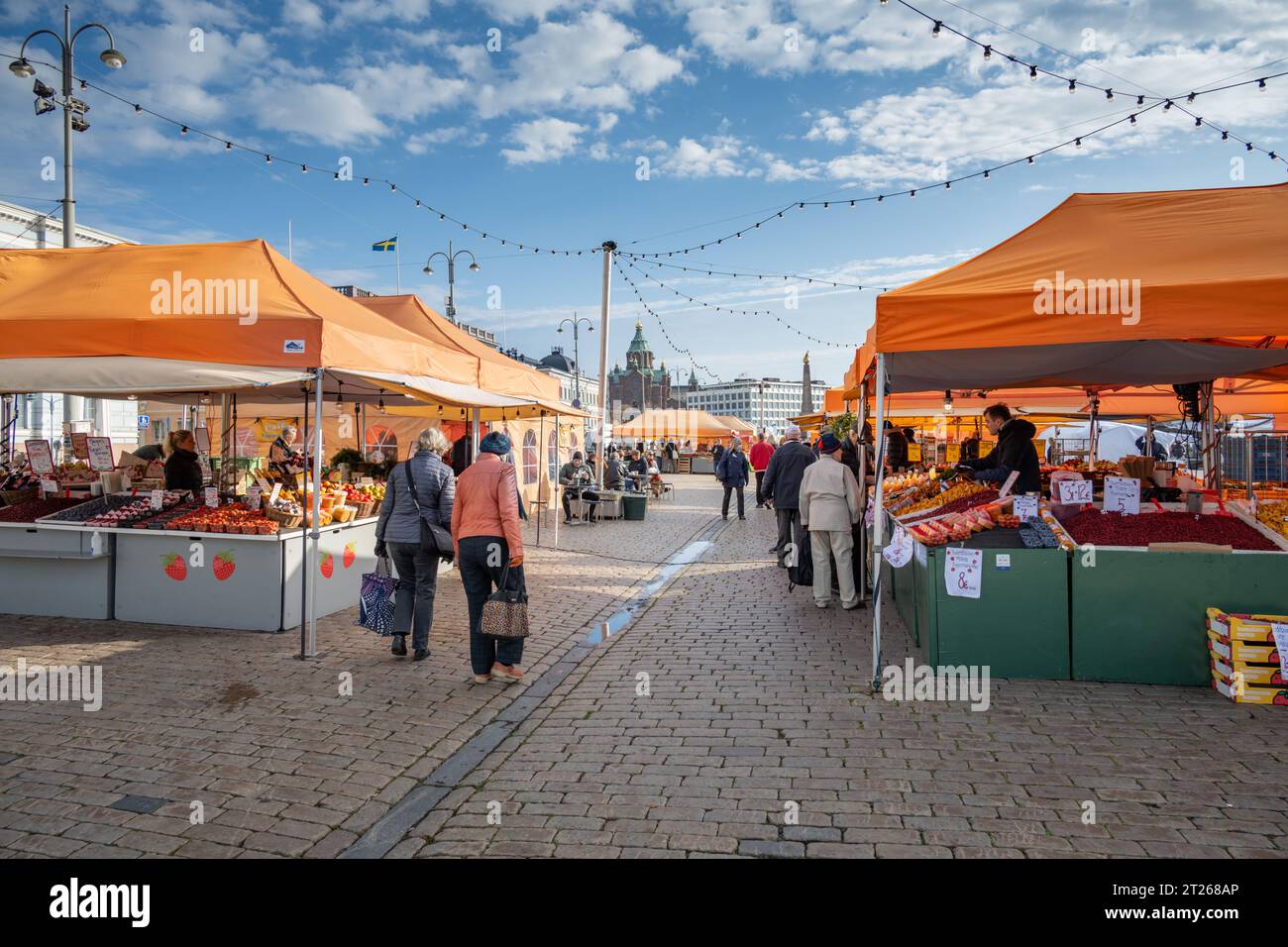 I clienti sfogliano prodotti freschi negli stand arancioni del mercato storico (Kauppatori) al porto meridionale di Helsinki, in Finlandia. Foto Stock