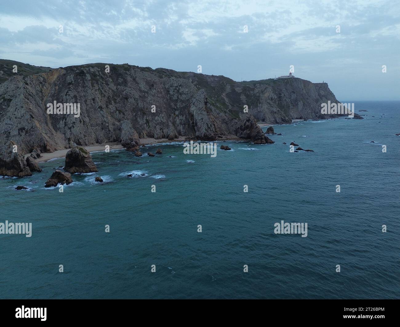 Una foto panoramica di un vasto specchio d'acqua che si estende all'orizzonte, con un ripido lato scogliera su un lato e una spiaggia sabbiosa sull'altro lato Foto Stock
