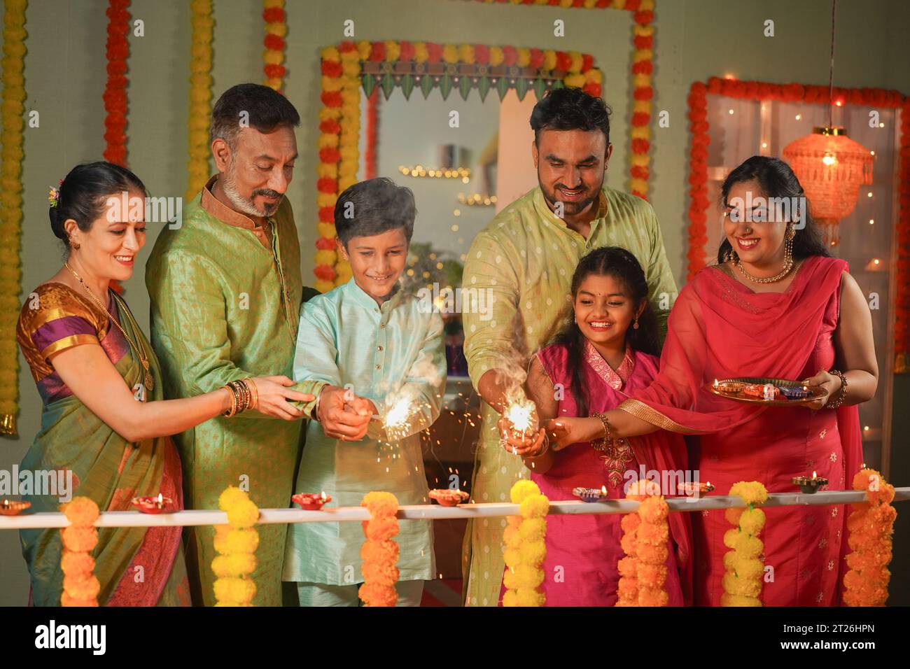 Gruppo di membri della famiglia che si divertono a vedere i bambini giocare con scintillanti o fuochi d'artificio durante la celebrazione del festival diwali a casa - concetto di Happy Foto Stock