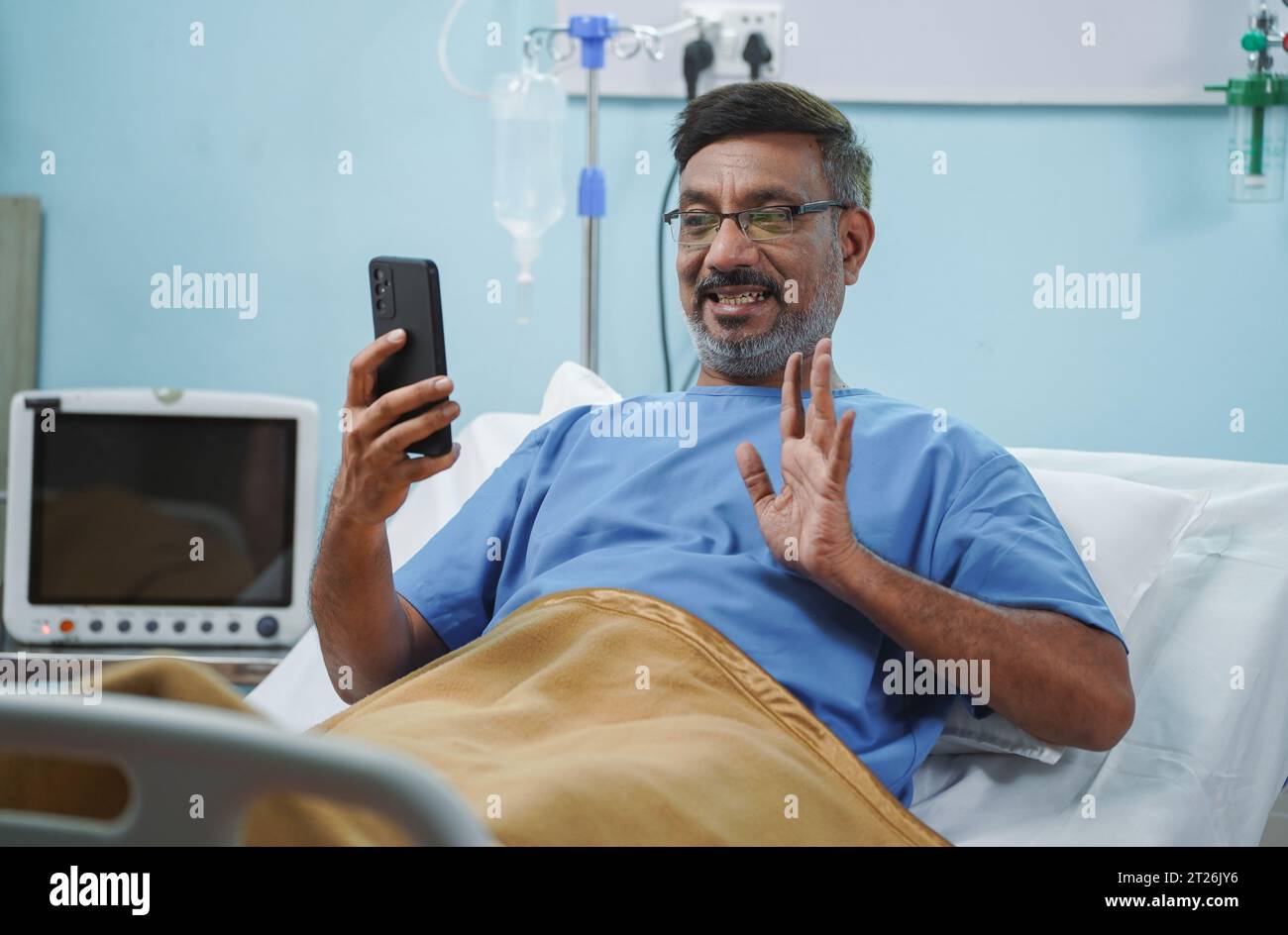 Anziano paziente anziano ammesso parlare in videochiamata utilizzando il telefono cellulare sul letto d'ospedale - concetto di recupero medico, trattamento di successo e Foto Stock