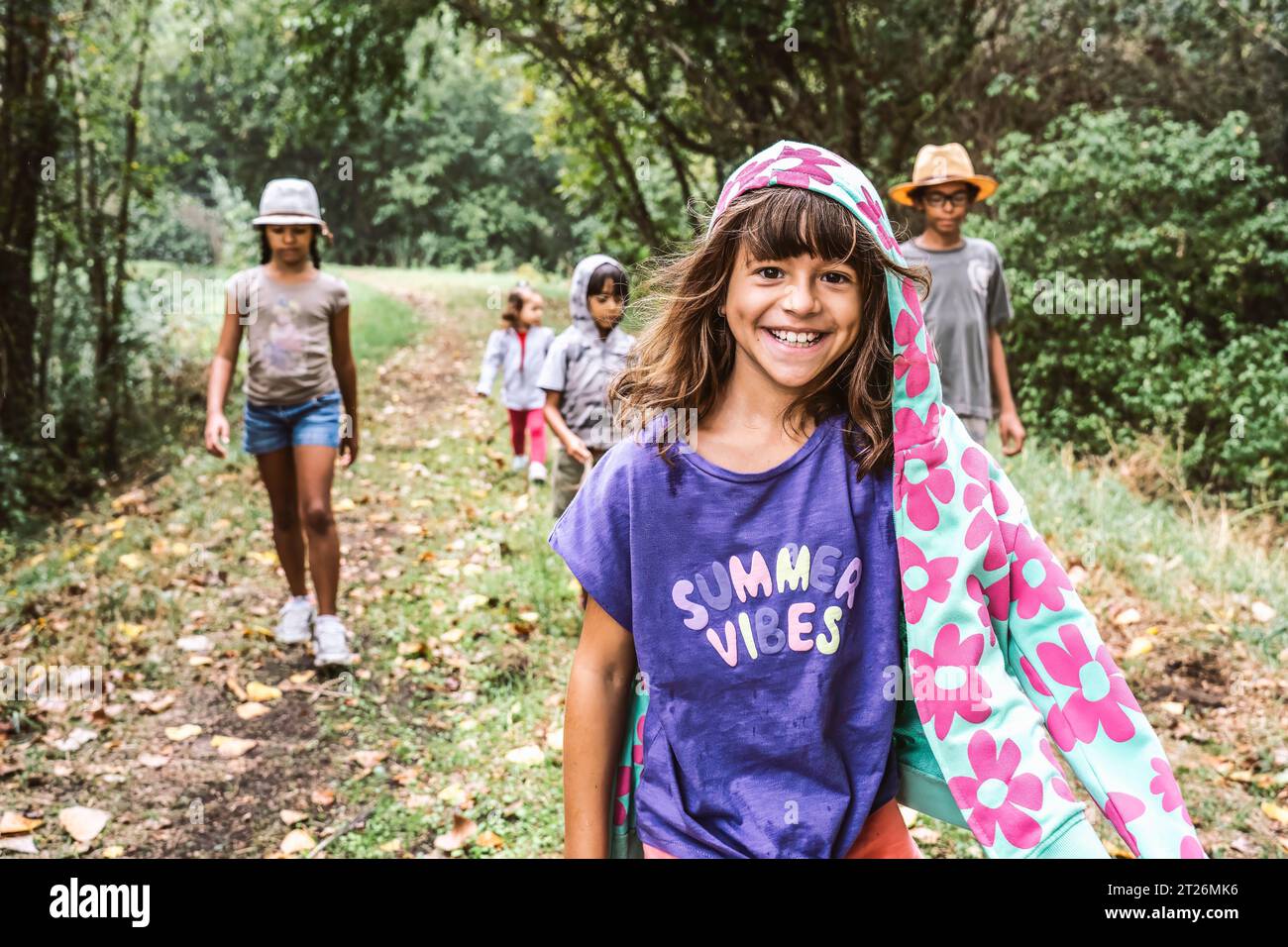 Giovane ragazza che cammina nella foresta con i suoi piccoli amici esploratori - concetto di giovani amanti della natura che proteggono il pianeta Terra - infanzia e natura Foto Stock