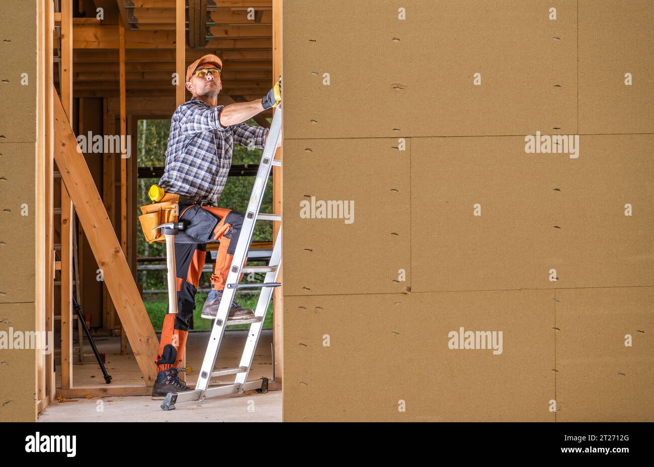 Lavoratore edile professionista all'interno del telaio della casa di nuova costruzione Foto Stock