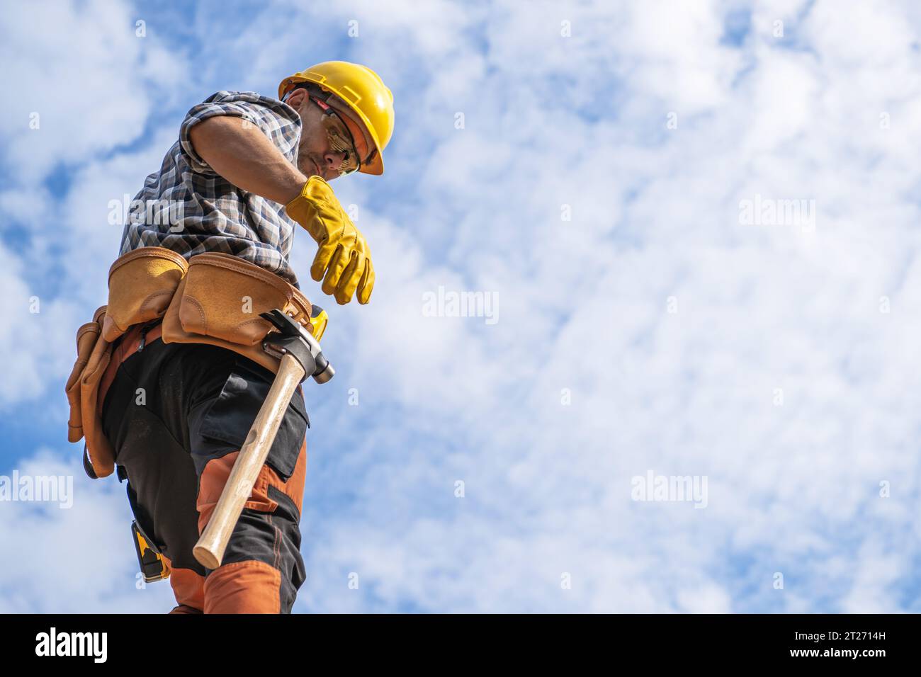 Lavoratore dell'area Hard Hat dell'appaltatore caucasico che si trova contro parzialmente Cloudy Sky che si prepara a lavorare Foto Stock