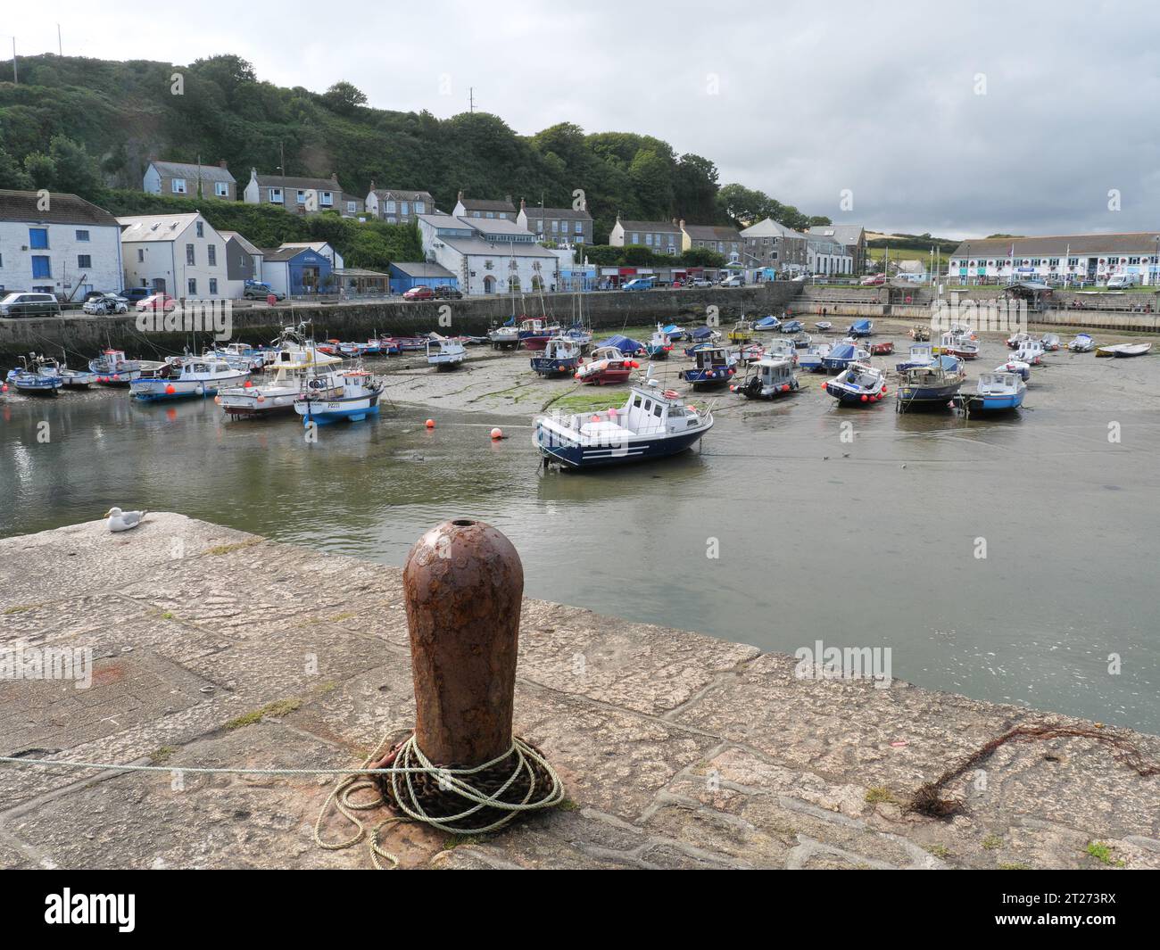 Barche da pesca colorate che si trovano sulla sabbia con la bassa marea nel porto di Porthleven, in Cornovaglia, Inghilterra Foto Stock