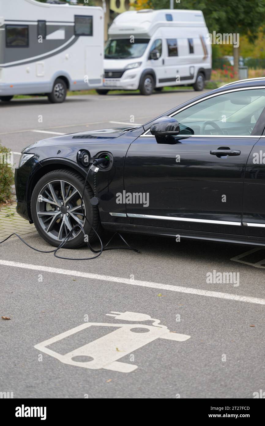 In un parcheggio per auto elettriche la batteria di un'auto nera viene ricaricata Foto Stock