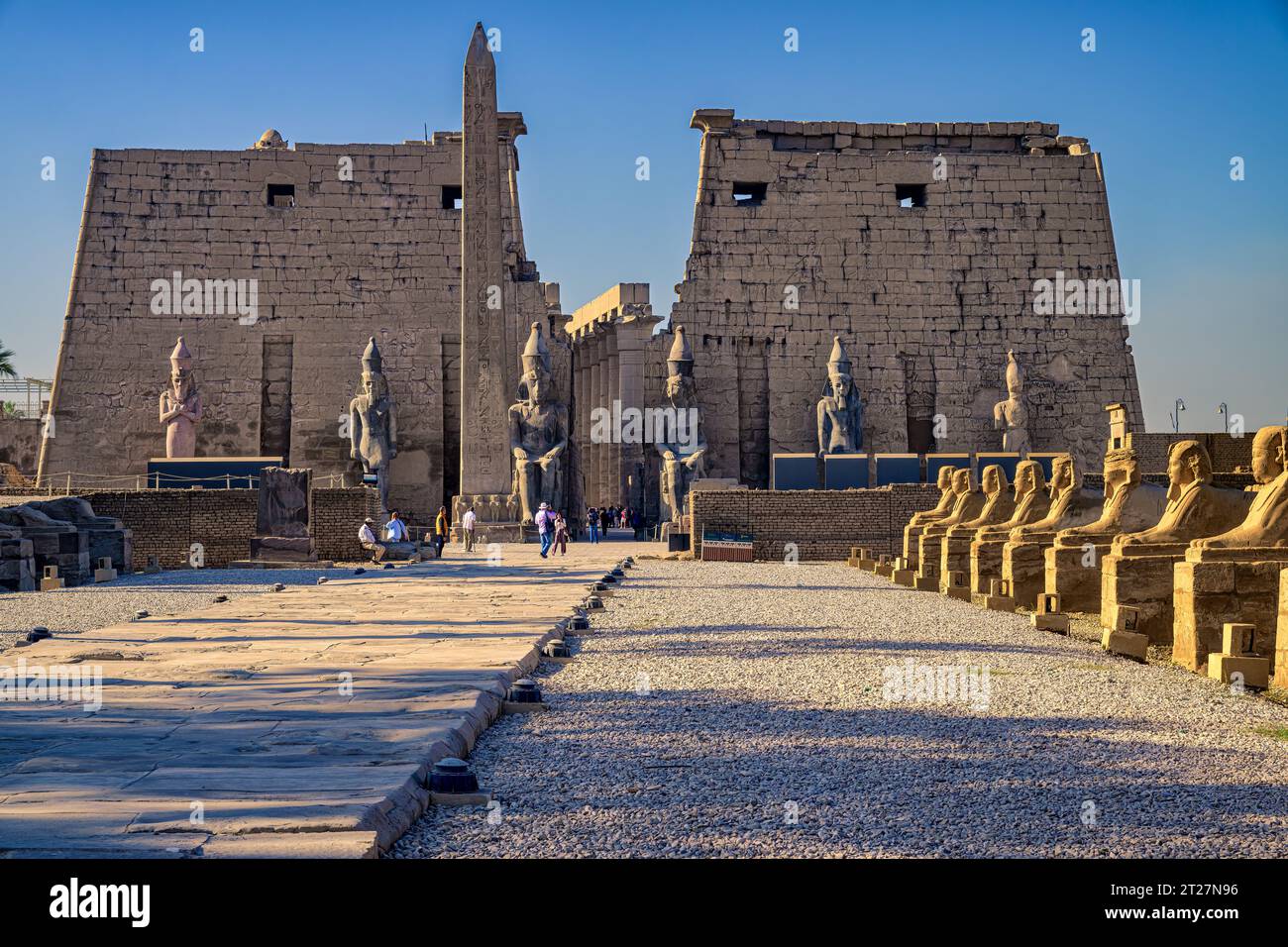 Le colossali statue di Ramsete II e l'obelisco nel primo pilone del Tempio di Luxor, viste dal viale delle Sfingi Foto Stock