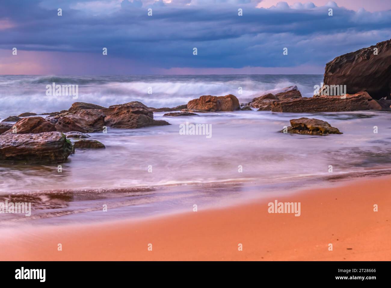 Alba al mare con nuvole, rocce e onde a Killcare Beach sulla Central Coast, New South Wales, Australia. Foto Stock