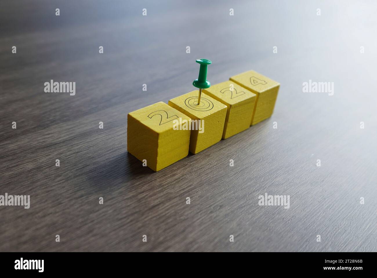Primo piano di un perno verde sulla parte superiore dei blocchi gialli con il numero 2024. Concetto di obiettivi e risoluzioni per l'anno nuovo Foto Stock