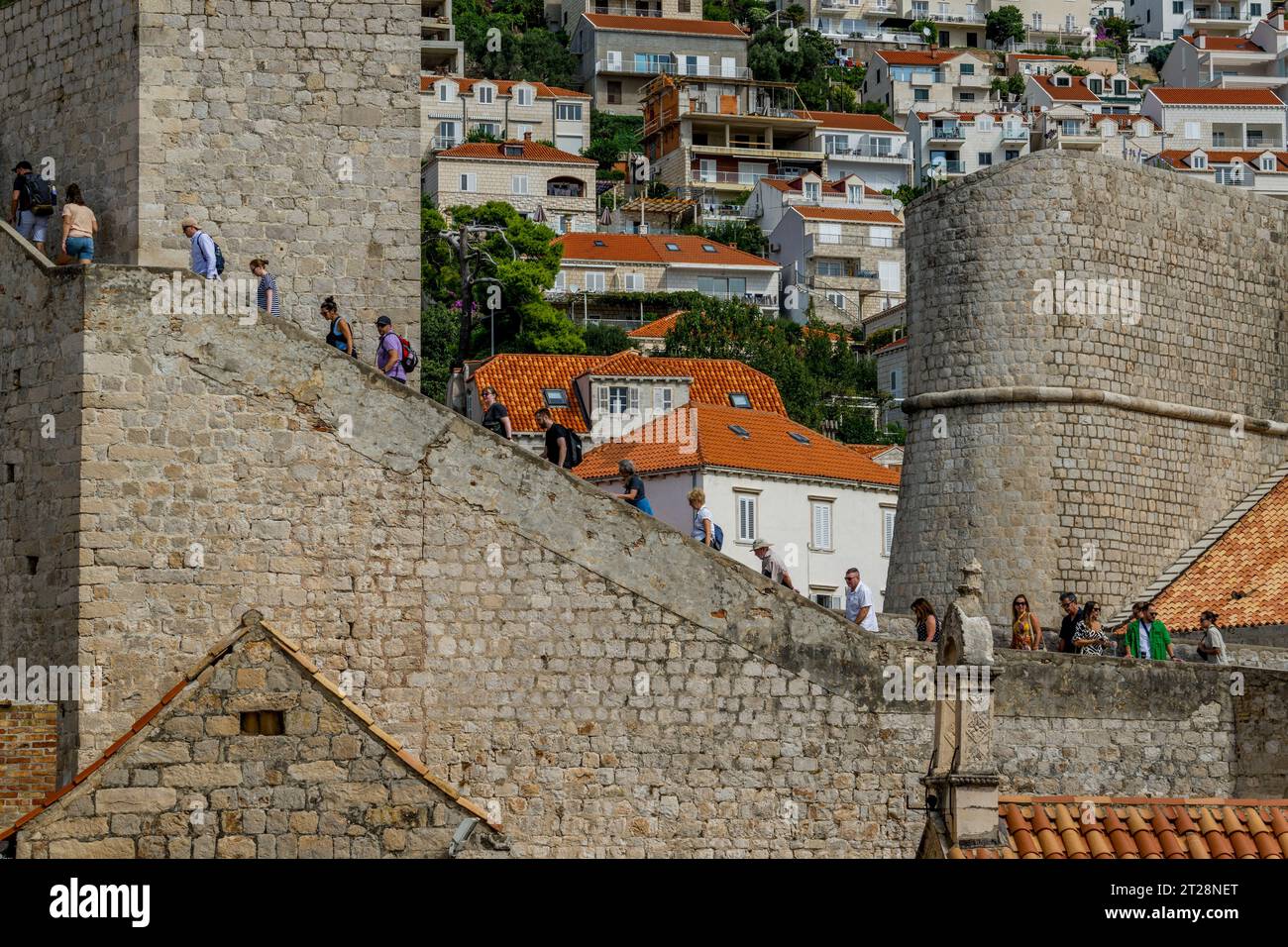 Vista dalla passeggiata delle mura della città delle persone che camminano fino alla Torre Gomji Ugao nella città vecchia di Dubrovnik, nel sud della Croazia. Foto Stock