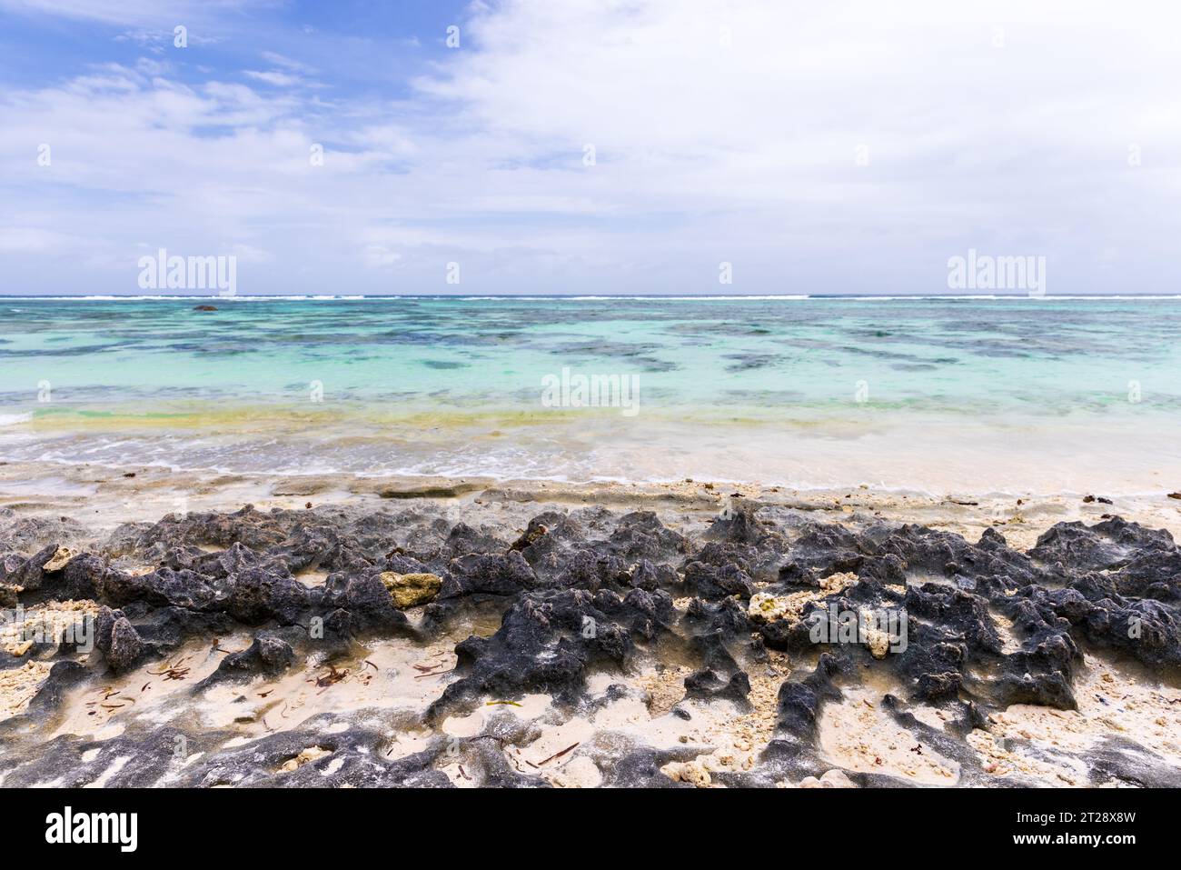 Rocce nere affilate sulla costa dell'isola di la Digue, vista sulla spiaggia di Anse Union. Paesaggio costiero. Seychelles Foto Stock