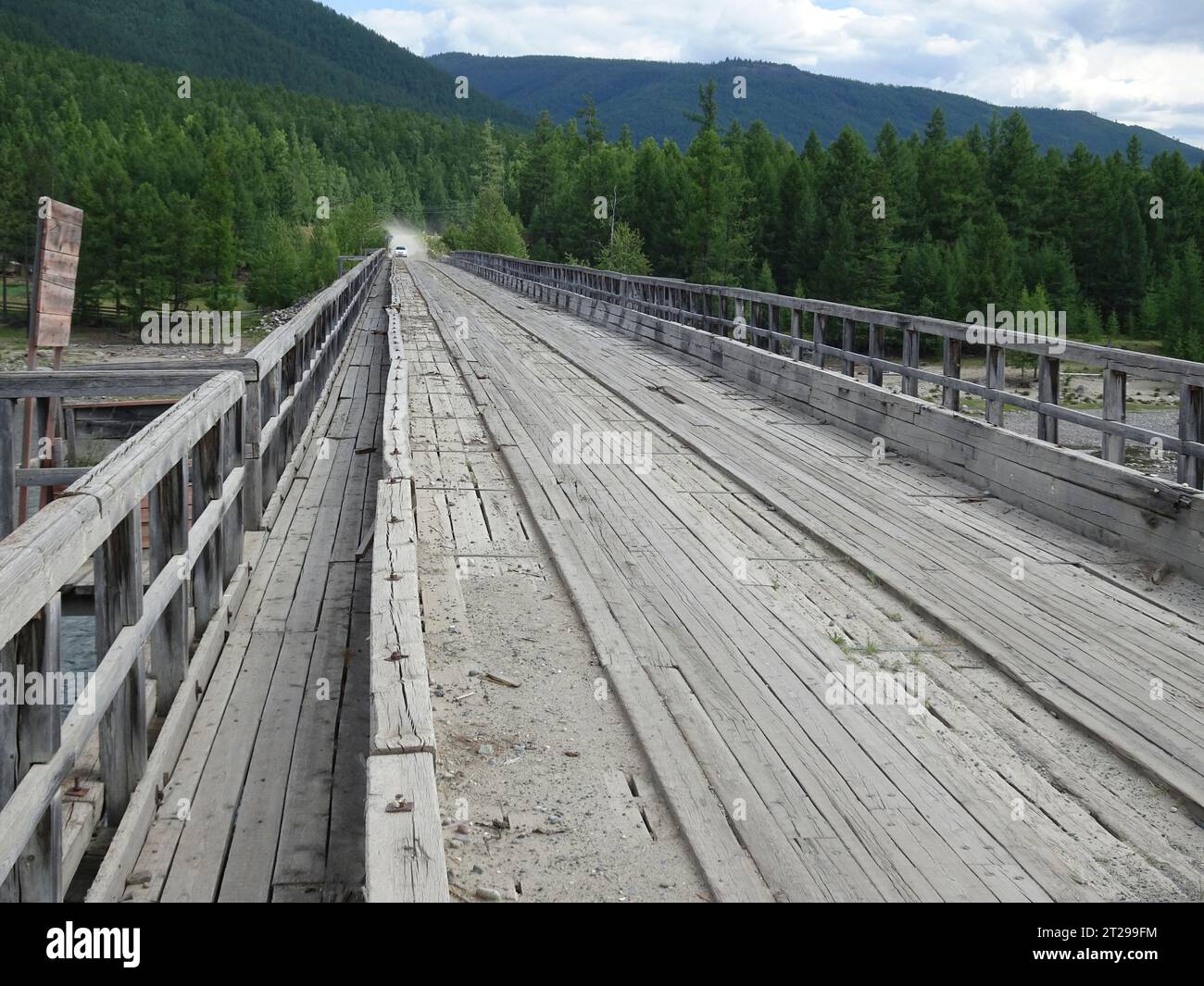 Un antico ponte di legno su un fiume in montagna, in una zona scarsamente popolata. Foto Stock