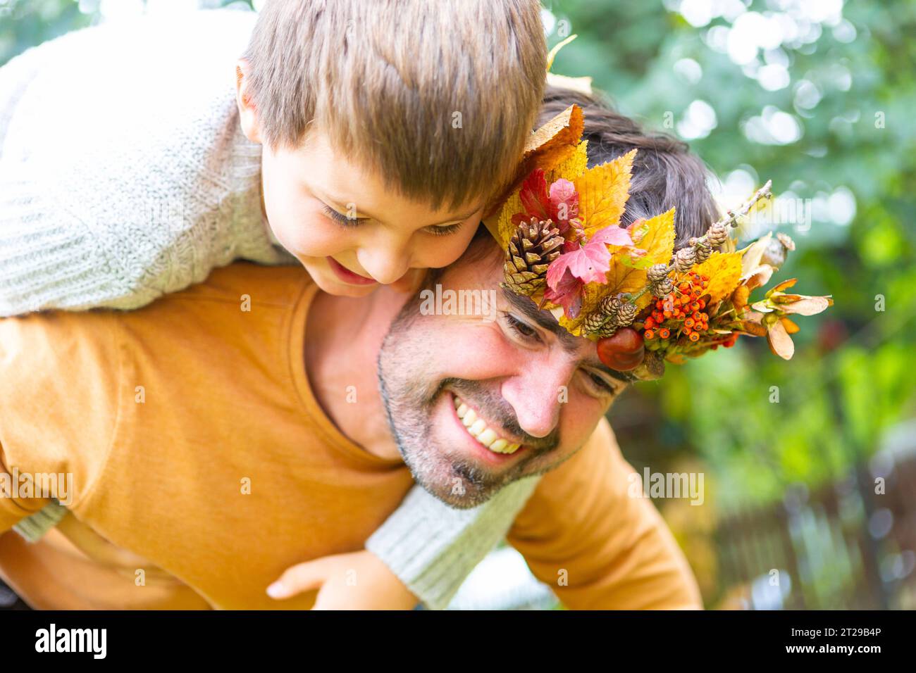 7 ottobre 2023: Papà e figlio giocano in giardino in autunno. Un piccolino che fa da schiena al padre con una corona autunnale fatta in casa di foglie colorate. Concetto di famiglia in autunno *** Papa und Sohn spielen im Herbst im Garten. Kleiner Junge Huckepack auf dem Rücken von seinem Vater mit einer herbstlichen selbstgebastelten Krone aus bunten Blättern. Familie im Herbst Konzept credito: Imago/Alamy Live News Foto Stock