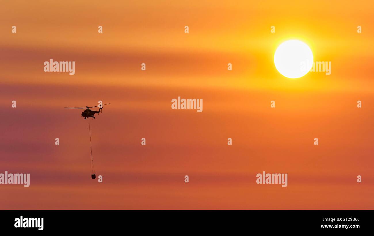 Elicottero antincendio al tramonto, cielo arancione, sole come disco luminoso, Falassarna, provincia di Chania, Creta, Grecia Foto Stock