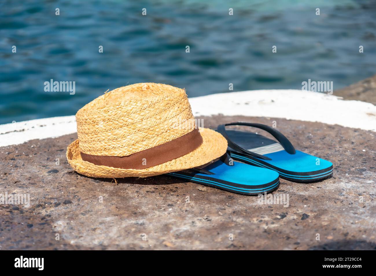 Cappello e ciabatte accanto a una piscina naturale, città costiera di Porto Moniz, Madeira Foto Stock