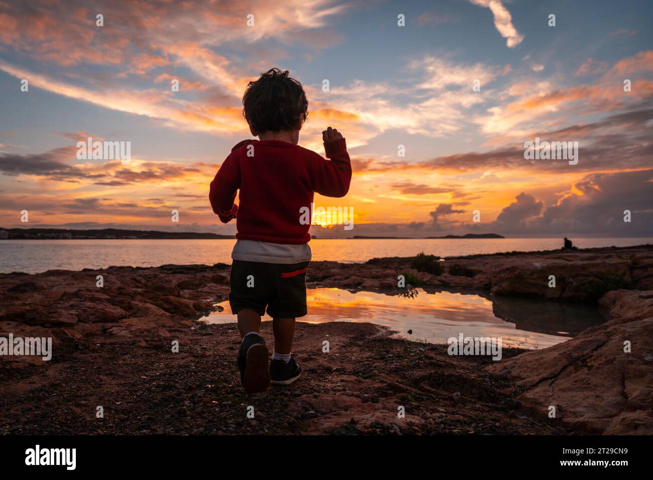 Tramonto a Ibiza in vacanza, un bambino che corre e ride in riva al mare a San Antonio Abad Foto Stock