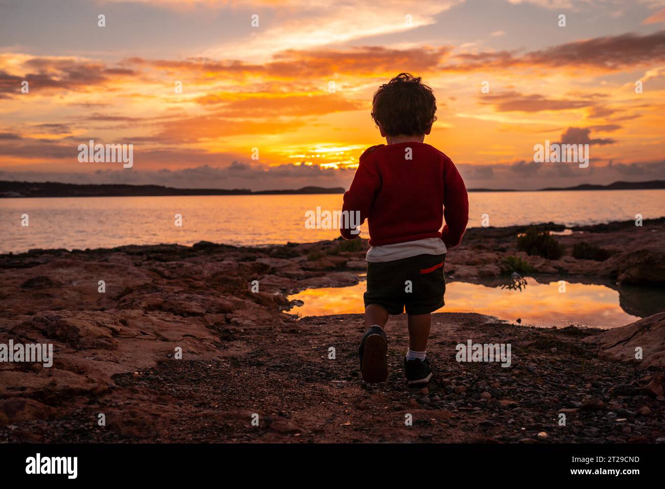 Tramonto a Ibiza in vacanza, un bambino che corre e ride in riva al mare a San Antonio Abad Foto Stock