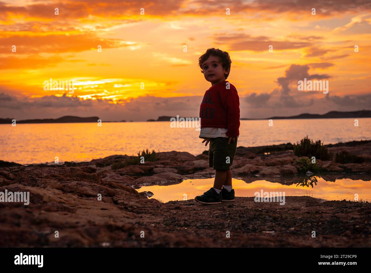 Tramonto a Ibiza in vacanza, un ragazzo di un anno che si diverte sul mare a San Antonio Abad Foto Stock