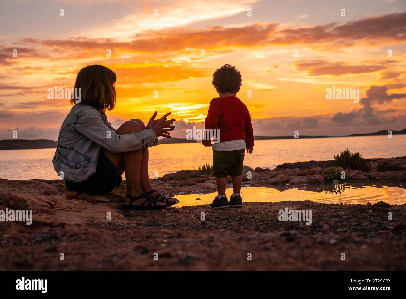 Madre con suo figlio sul lungomare al tramonto a San Antonio Abad, isola di Ibiza Foto Stock