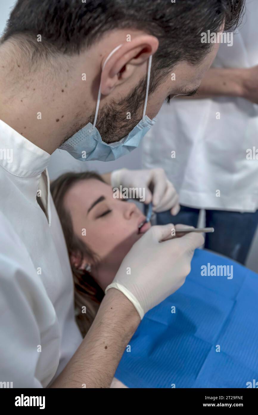 Una dentista donna cura i denti di un paziente. Il dentista effettua una pulizia professionale dei denti di una giovane paziente nello studio dentistico. Foto Stock
