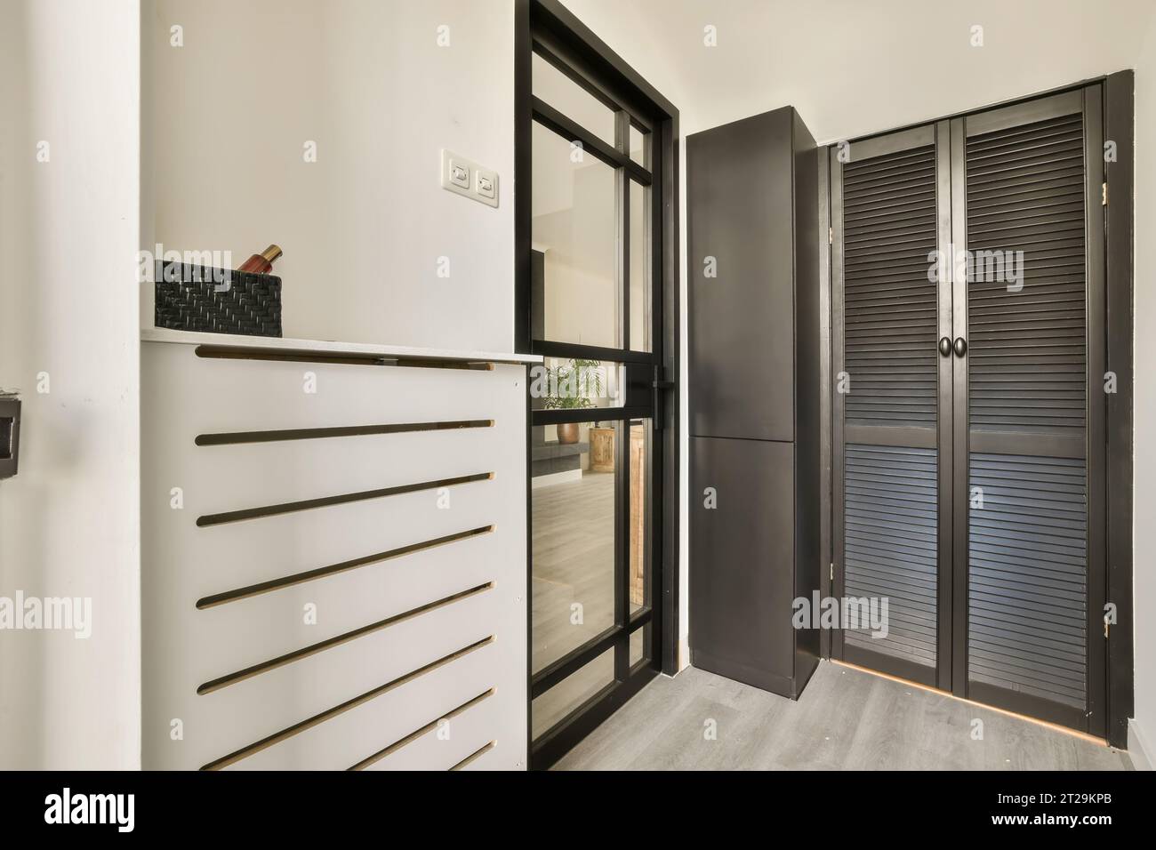 Interno di un corridoio vuoto con porte nere chiuse e pareti bianche in un appartamento contemporaneo Foto Stock