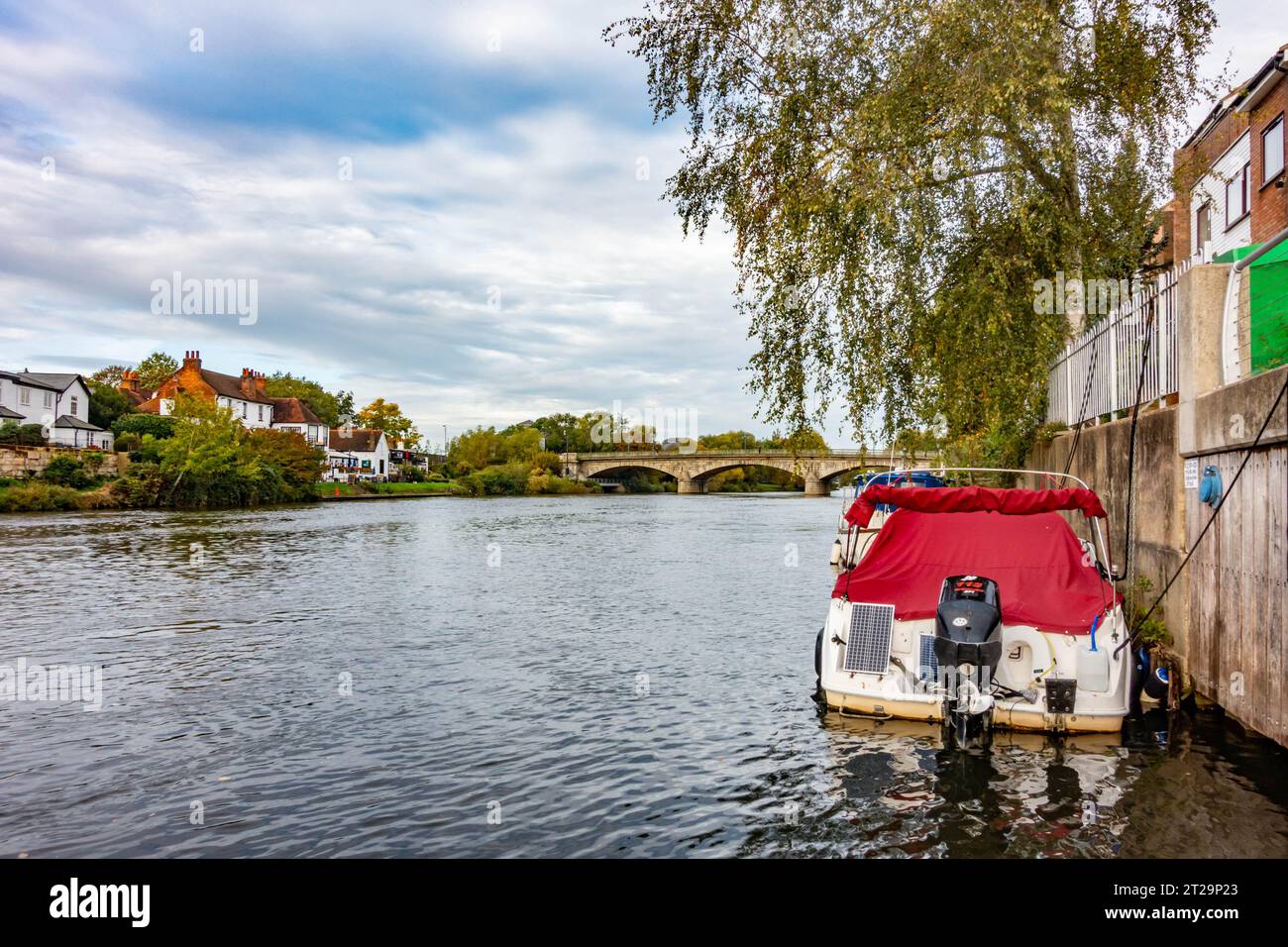 Vista lungo il Tamigi verso Staines Bridge con un motoscafo ormeggiato sul lato del fiume nel Surrey, Regno Unito Foto Stock