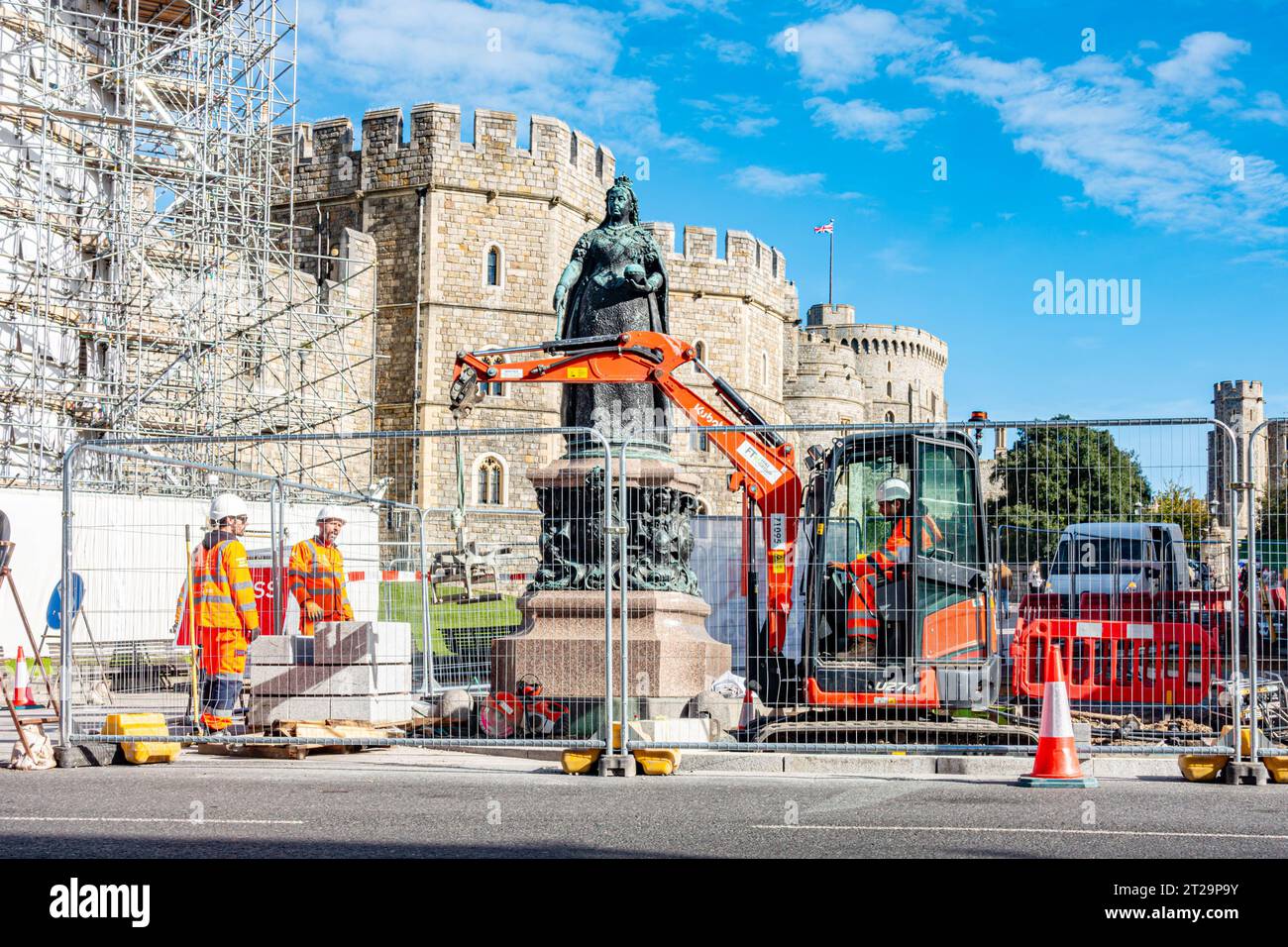 Lavori stradali all'esterno del Castello di Windsor intorno alla statua di bronzo della Regina Vittoria. L'area è recintata mentre gli operai scavano la strada. Foto Stock