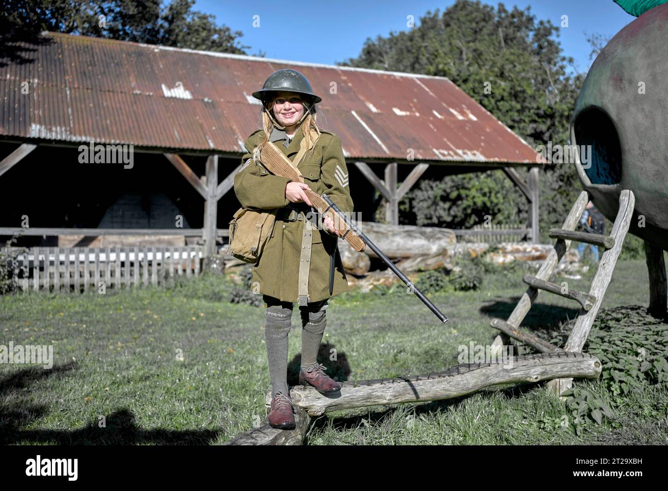 Giovane ragazza vestita in uniforme dell'esercito britannico della seconda guerra mondiale e con un fucile in una rievocazione della seconda guerra mondiale degli anni '1940, Avoncroft Museum Bromsgrove, Inghilterra Regno Unito Foto Stock