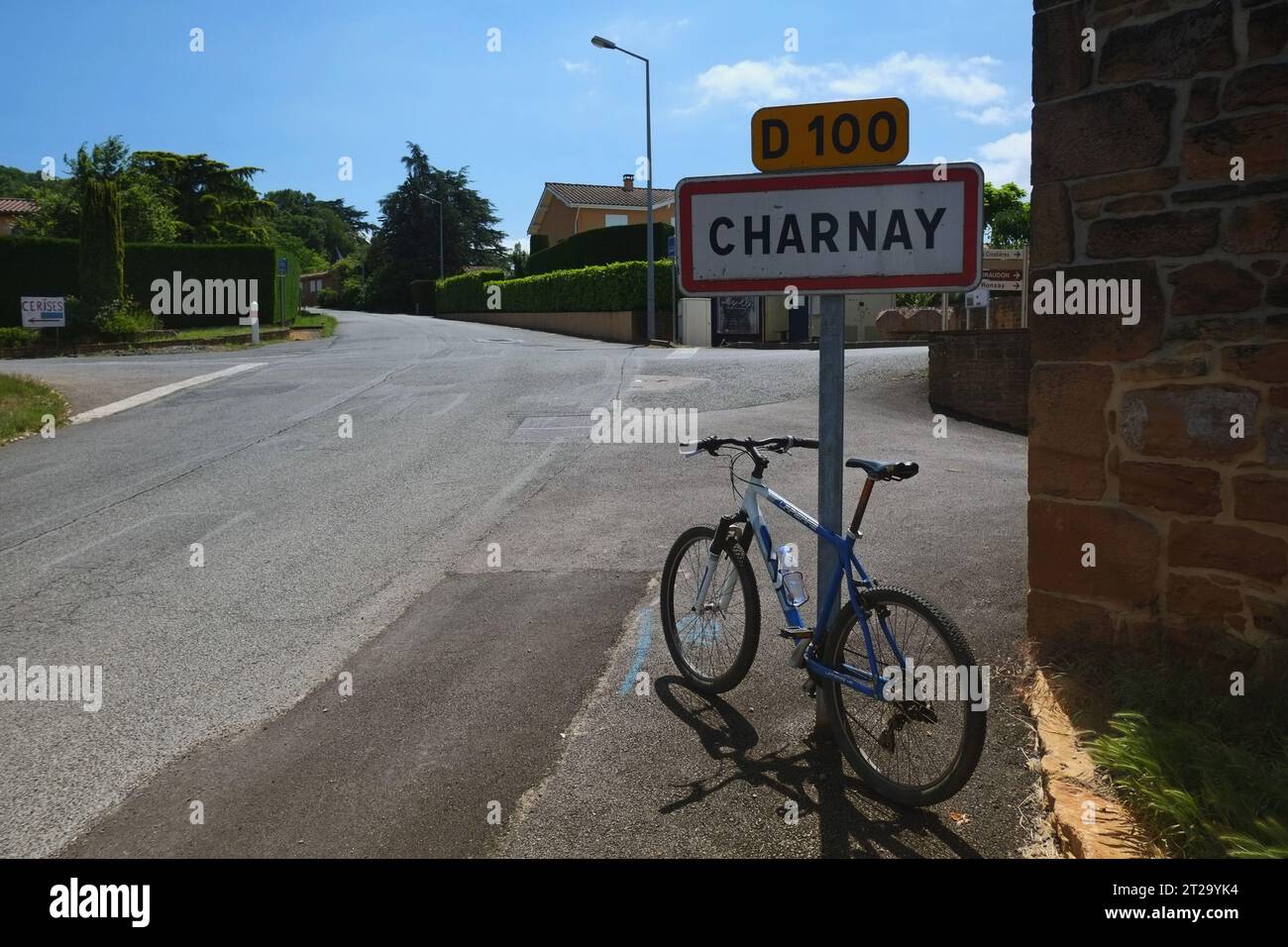 Una mountain bike appoggiata contro il cartello stradale per Charnay, un villaggio medievale in cima a una collina nella regione vinicola francese del Beaujolais Foto Stock