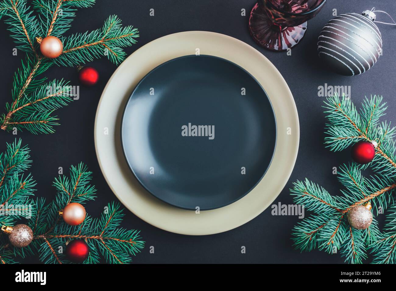 Elegante tavolo con rami di abete e palline di Natale, piatto nero su sfondo nero. Concetto di Natale. Vista dall'alto, base piatta. Foto Stock