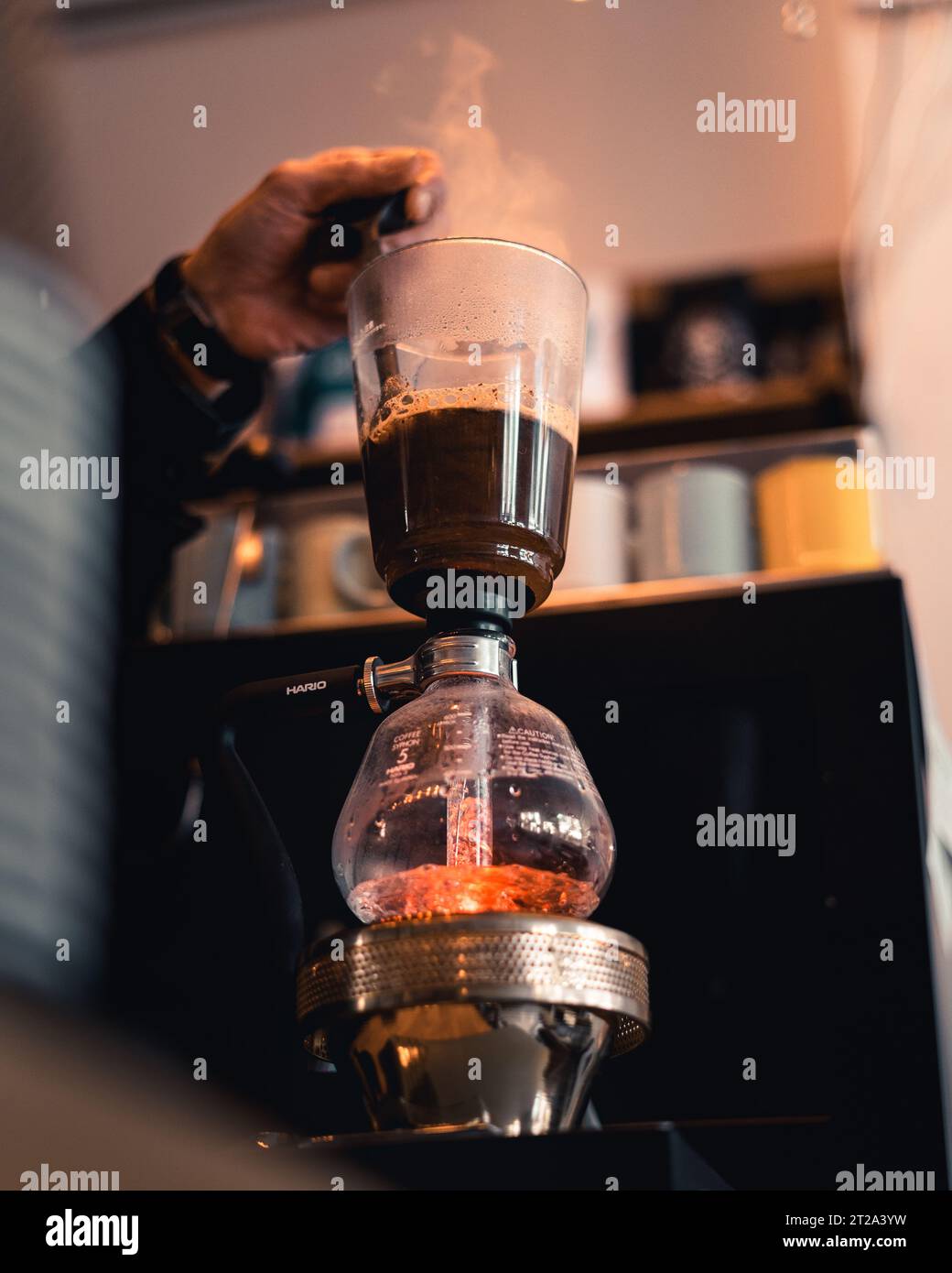 Un'immagine secondaria del processo di preparazione di un caffè sifone giapponese, mescolando i chicchi di caffè freschi. Foto Stock