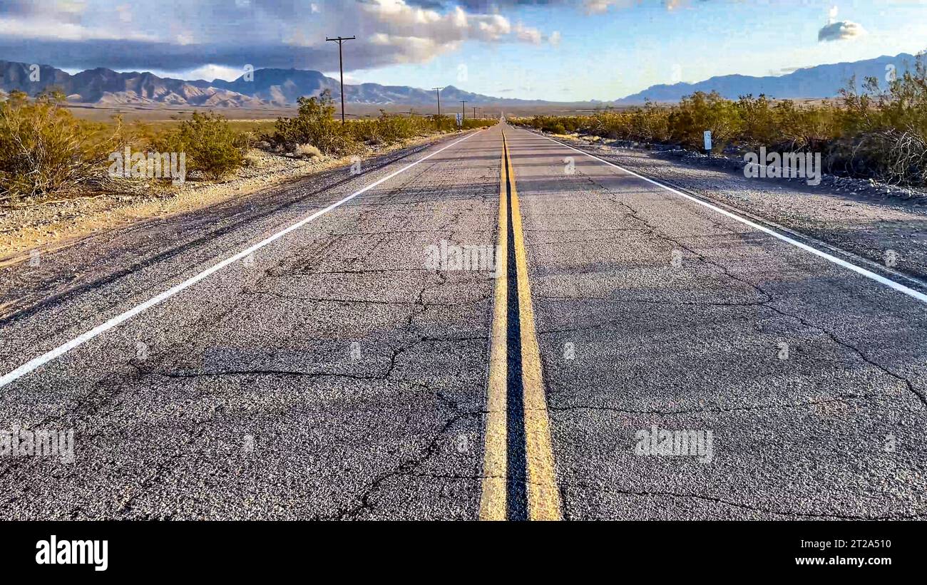 La linea gialla continua una segnaletica stradale sul marciapiede di un'autostrada infinita sulla US Route 66, questo tratto di autostrada attraversa il deserto del Mojave. Foto Stock