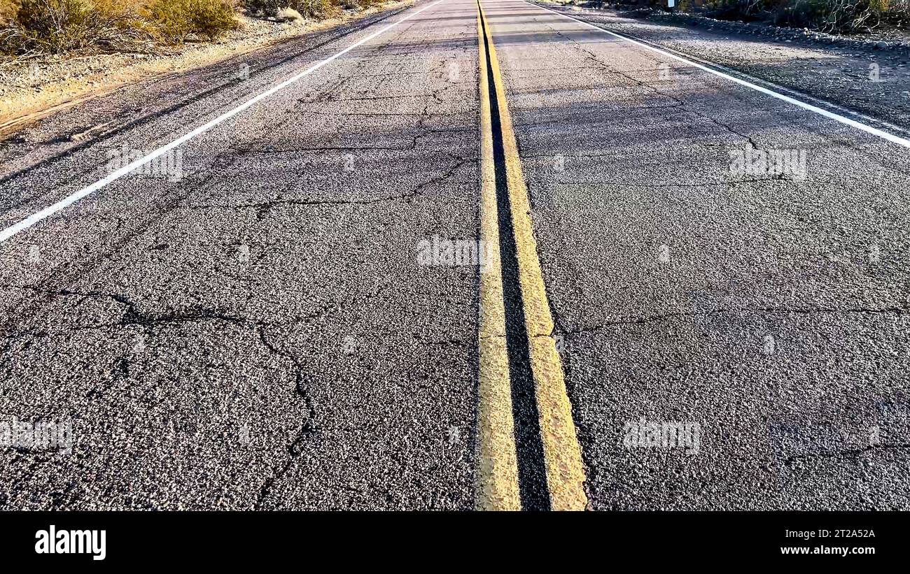 Linea gialla continua segnaletica stradale sul marciapiede stradale, sull'autostrada che attraversa il deserto nel Mojave da Los Angeles in California. Foto Stock
