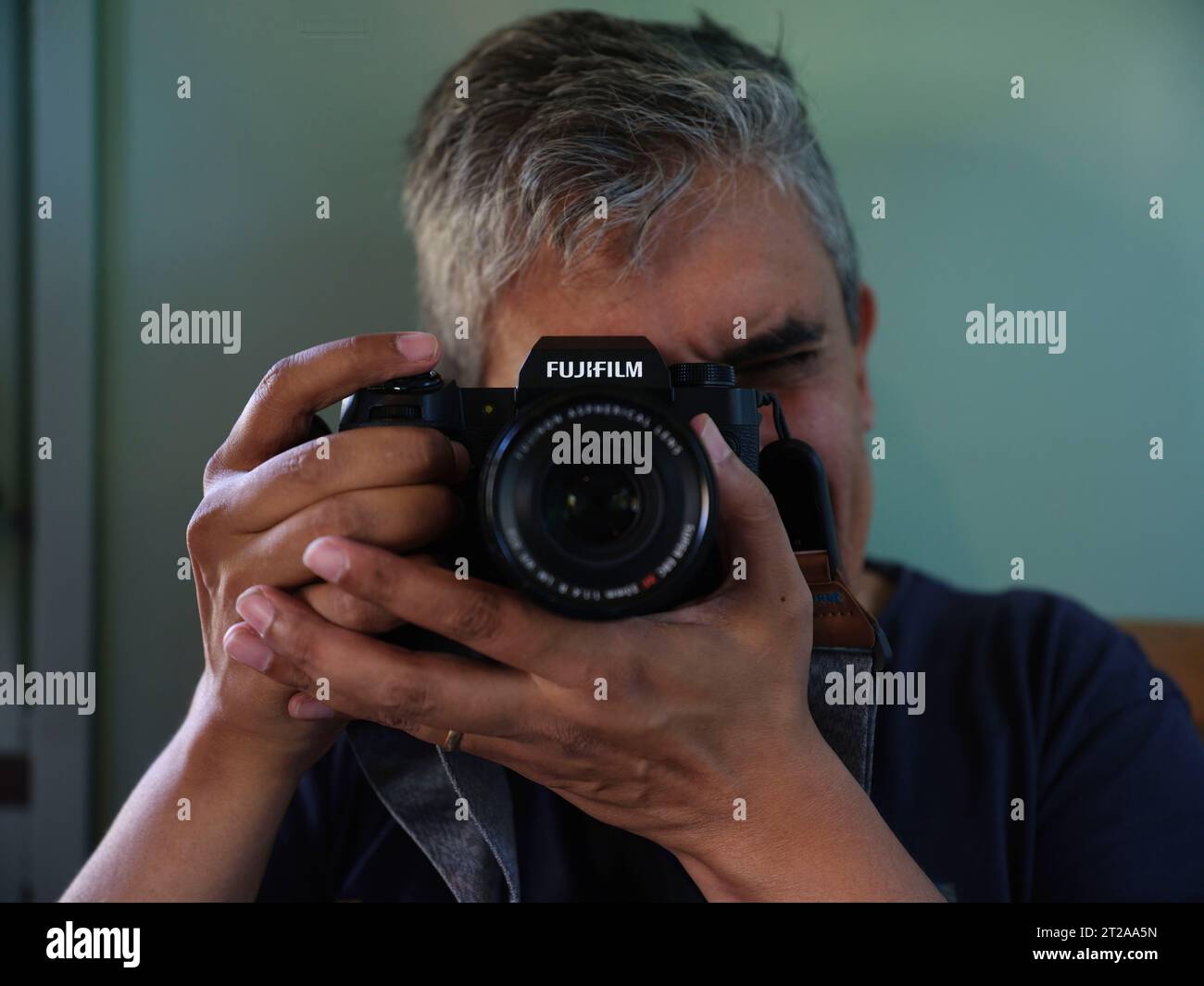 Uomo che scatta foto con la sua fotocamera Fujifilm mirrorless Foto Stock